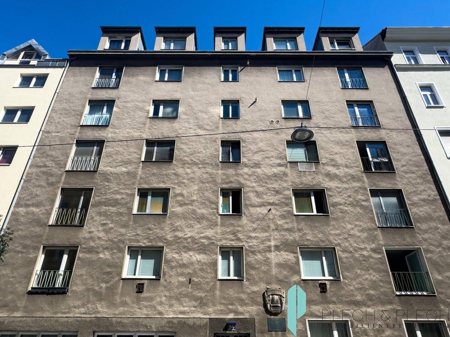 Fassade eines Mehrfamilienhauses mit vielen Fenstern und Balkonen.