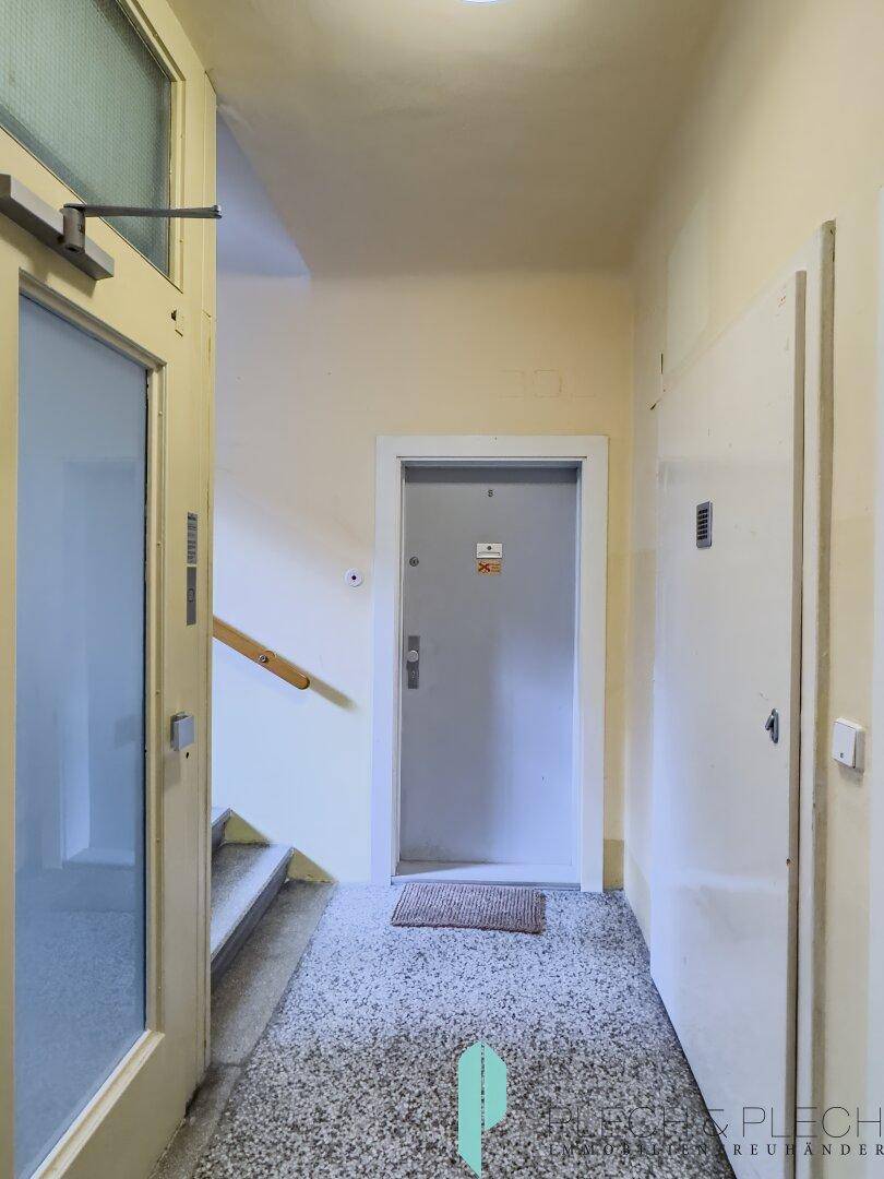 Eingangsbereich des Gebäudes mit Treppe und Zugang zum Aufzug.