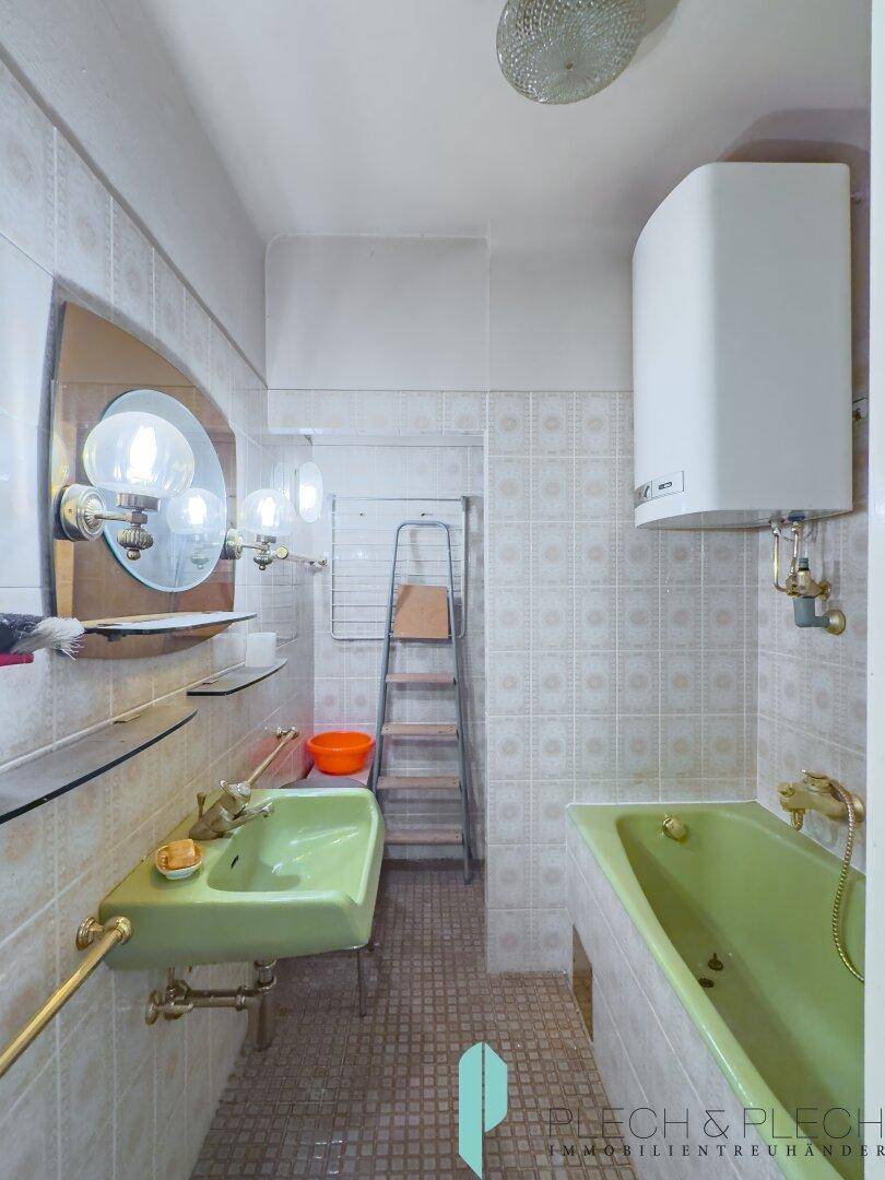 Badezimmer im 80er-Jahre-Stil mit grüner Badewanne und Waschbecken.