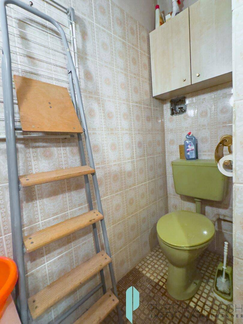 Separate Toilette im 80er-Jahre-Stil mit grüner Keramik und Fliesen.