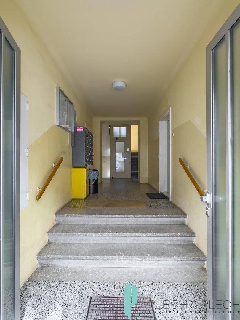 Eingangsbereich des Gebäudes mit Treppe und Blick auf die Straße.