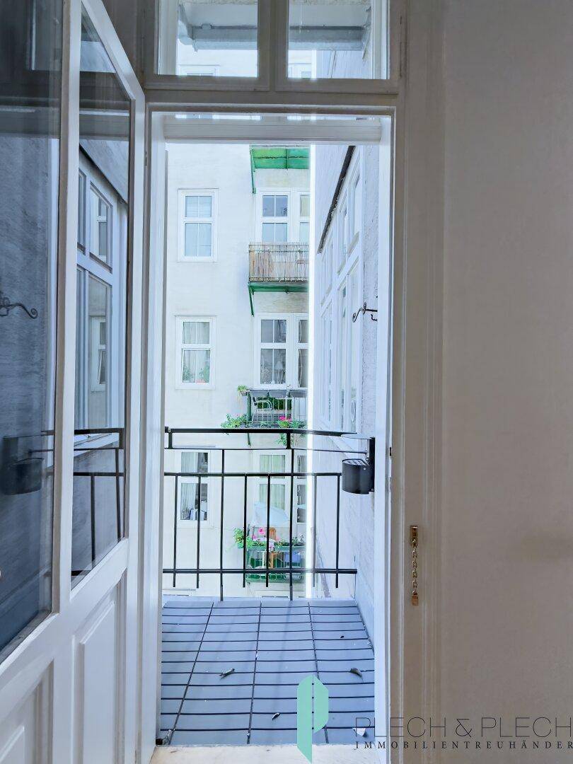 Kleiner Balkon mit Fliesenboden und Blick auf den Innenhof des Gebäudes.