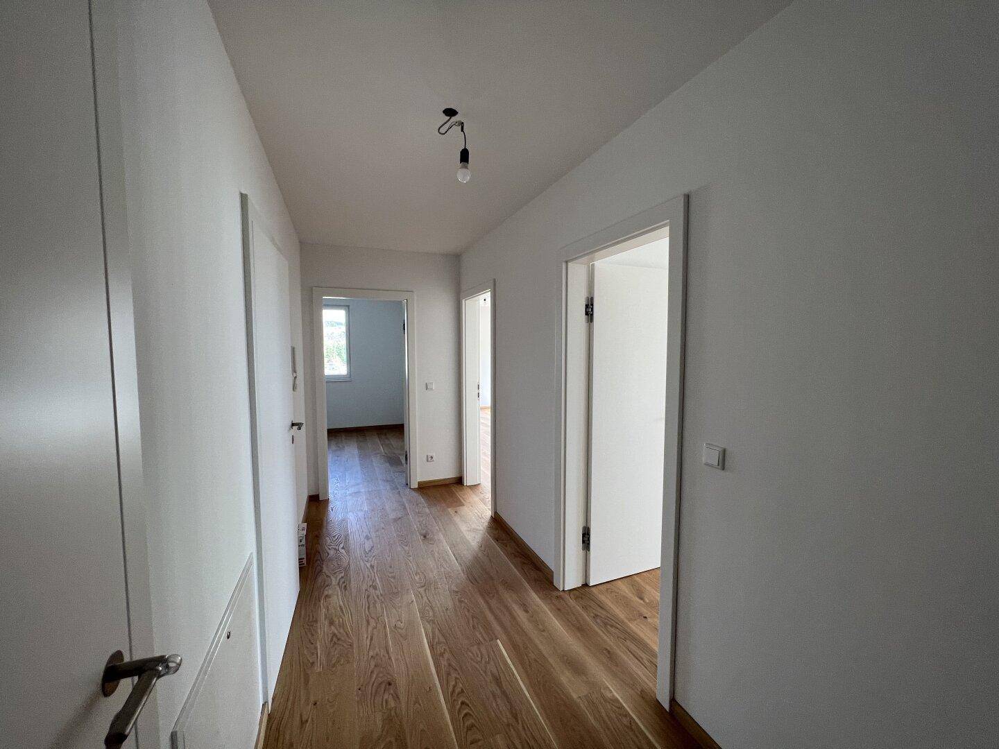 Heller Flur mit Holzboden, der zu verschiedenen Räumen der Wohnung führt.