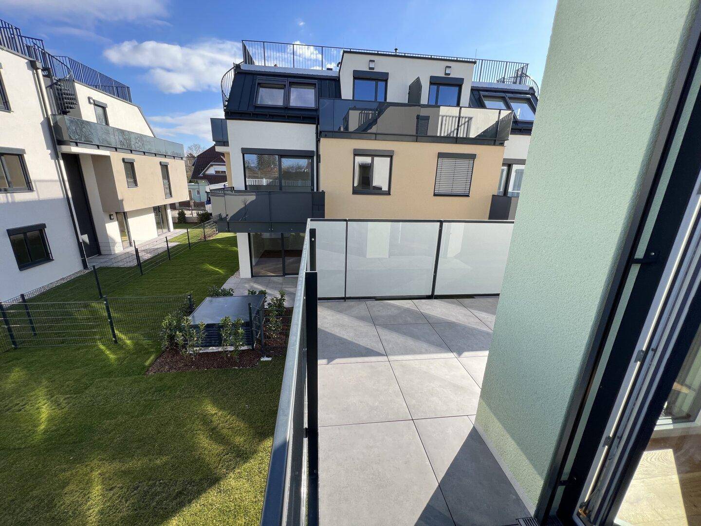 Blick vom Balkon auf die umliegenden Neubauten und den grünen Gartenbereich.