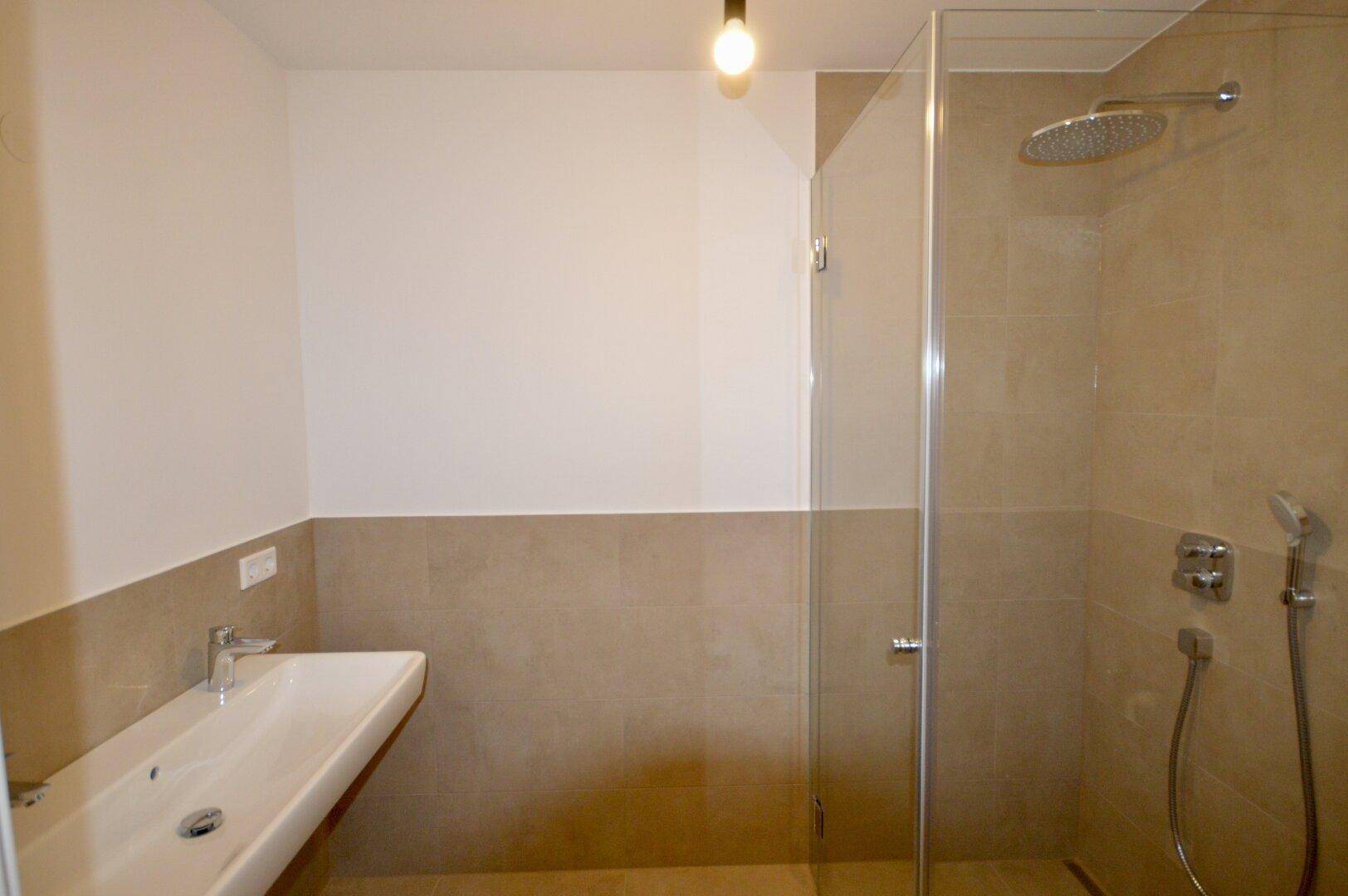 Modernes Badezimmer mit begehbarer Dusche, Regenduschkopf und eleganten beigefarbenen Fliesen.