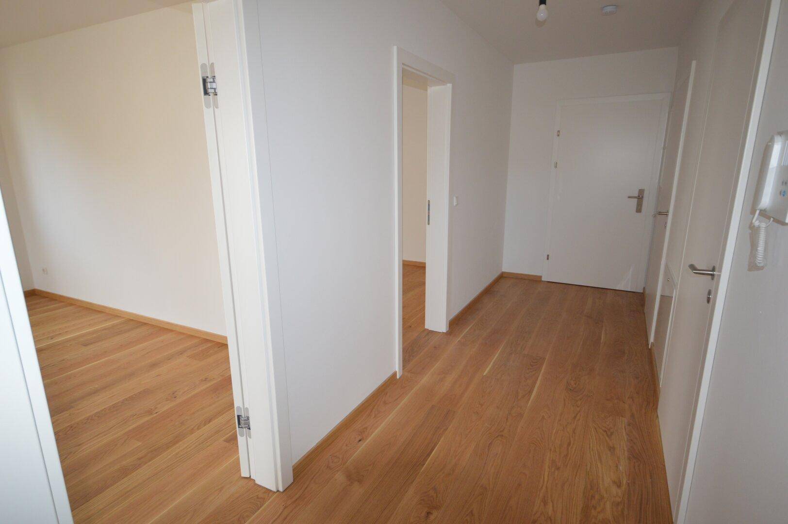 Heller Flur mit Holzboden und weißen Türen, der die verschiedenen Wohnbereiche verbindet.