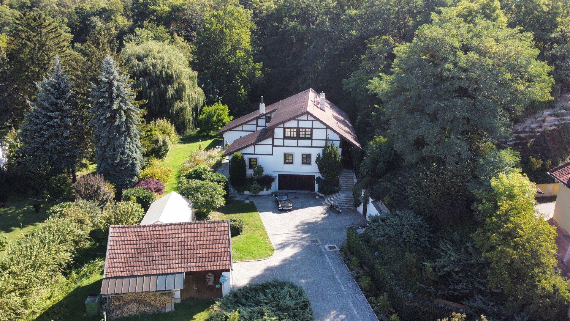 Luftaufnahme des Anwesens mit Haupthaus, Nebengebäude und weitläufigem Gartenbereich.