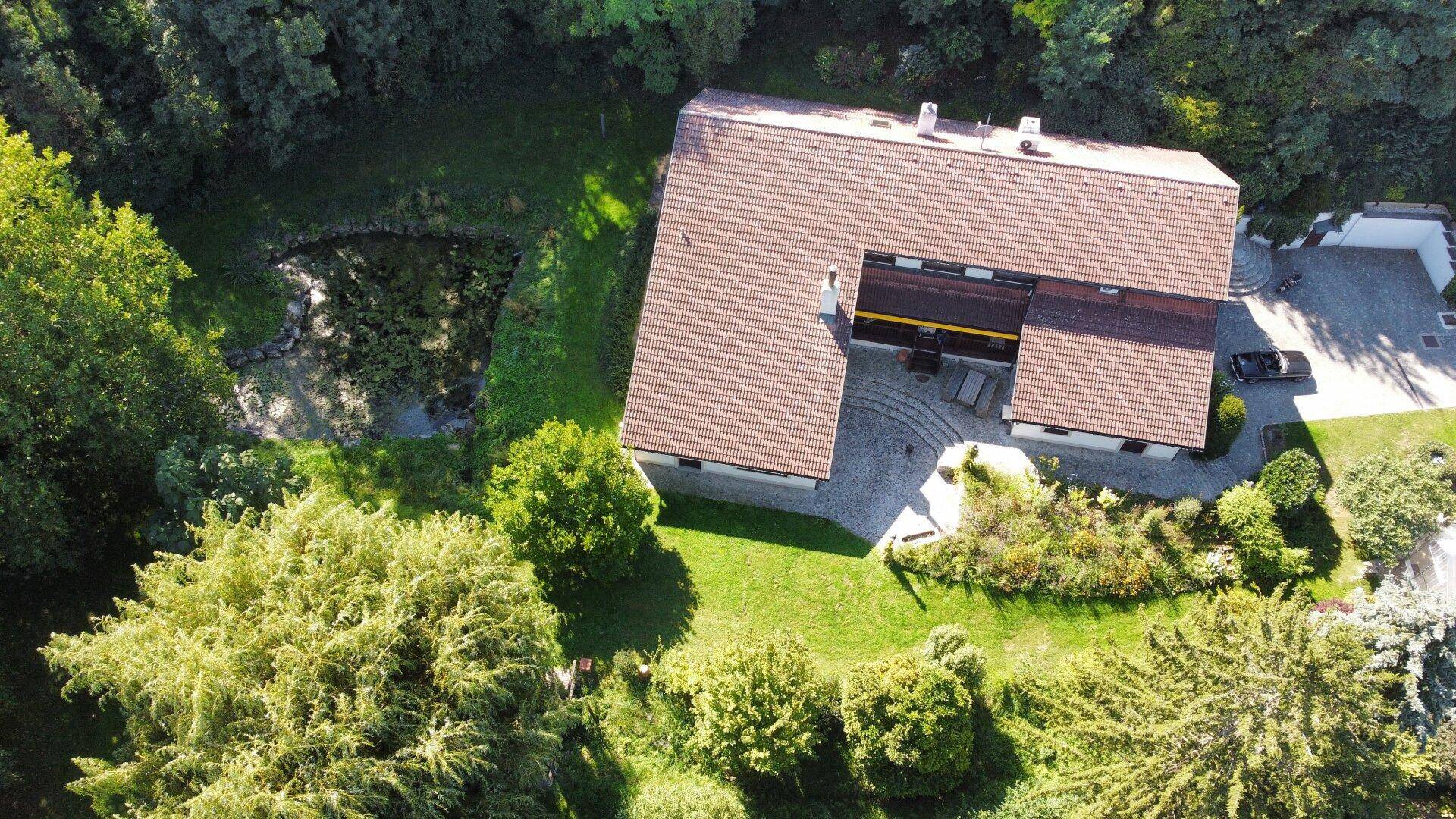 Dachansicht des Hauses mit großer gepflasterter Terrasse und angrenzendem Garten.