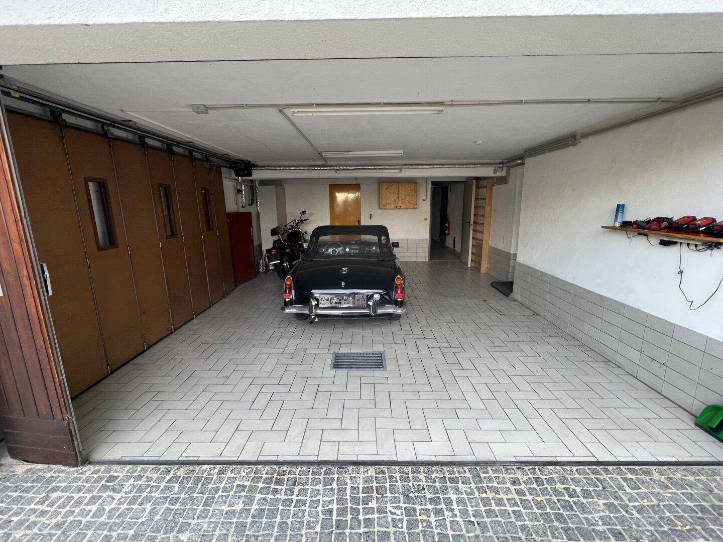 Geräumige Garage mit Fliesenboden und Platz für mehrere Fahrzeuge.