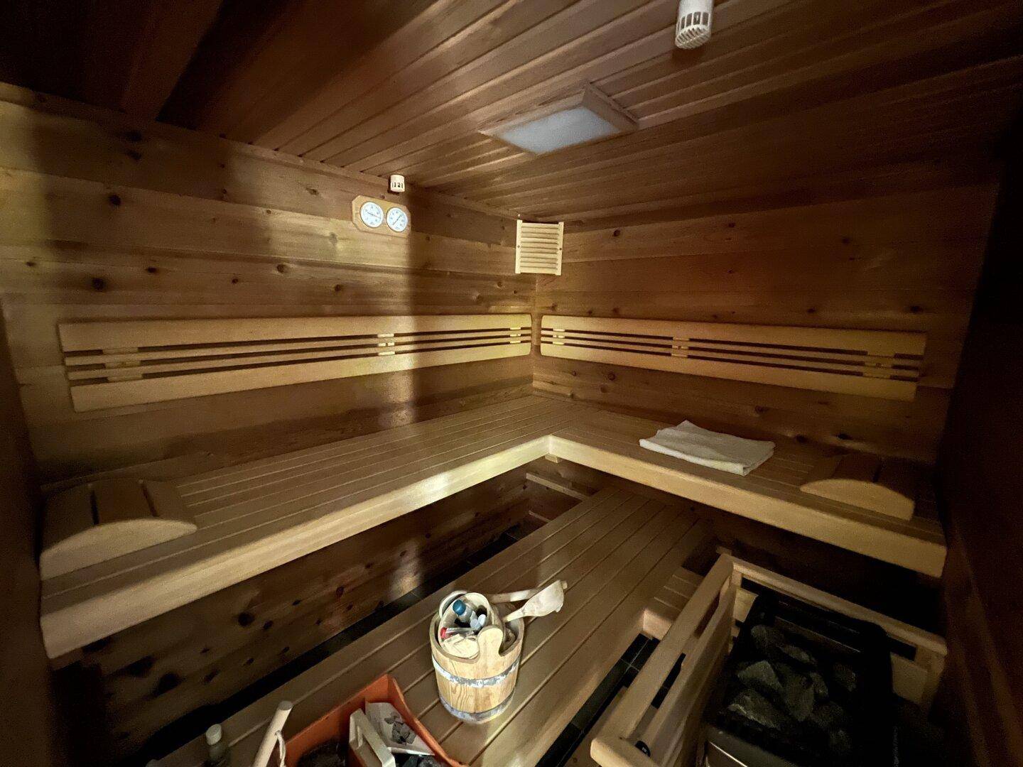 Gemütliche Holzsauna mit mehreren Bänken und traditionellem Saunaofen.