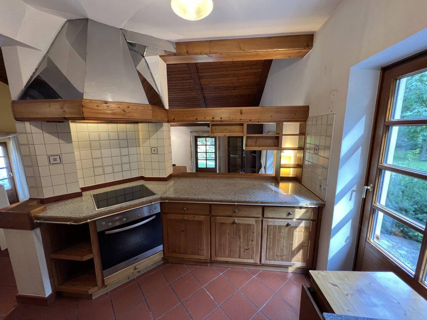 Traditionelle Küche mit Holzschränken, Granitarbeitsplatte und Terracottaboden.