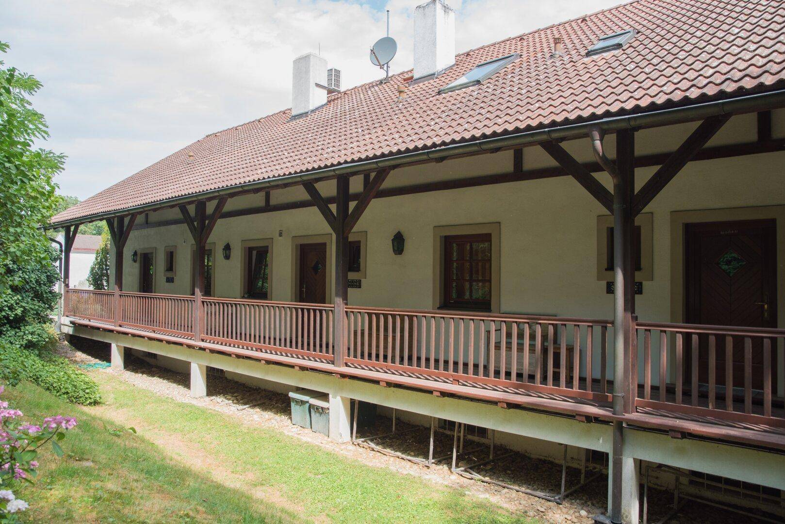 Weitläufige, überdachte Loggia mit Holzbalken und Blick auf die grüne Umgebung.