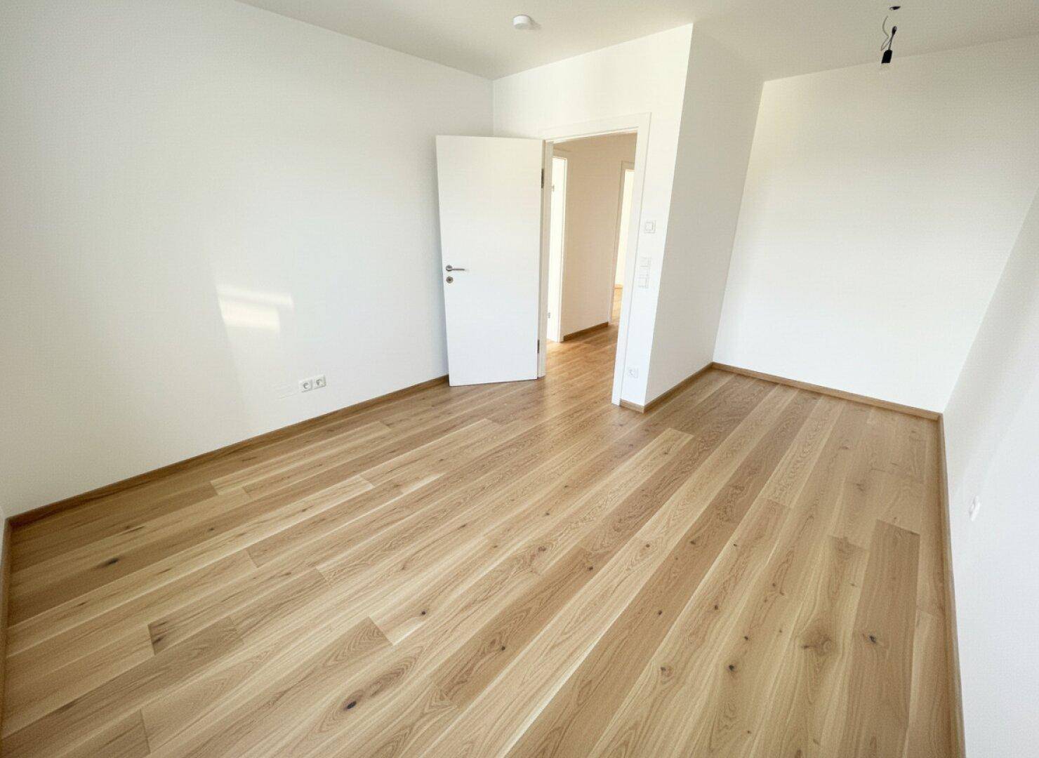 Geräumiges Zimmer mit Holzboden und weiß gestrichenen Wänden, ideal für individuelle Gestaltung.