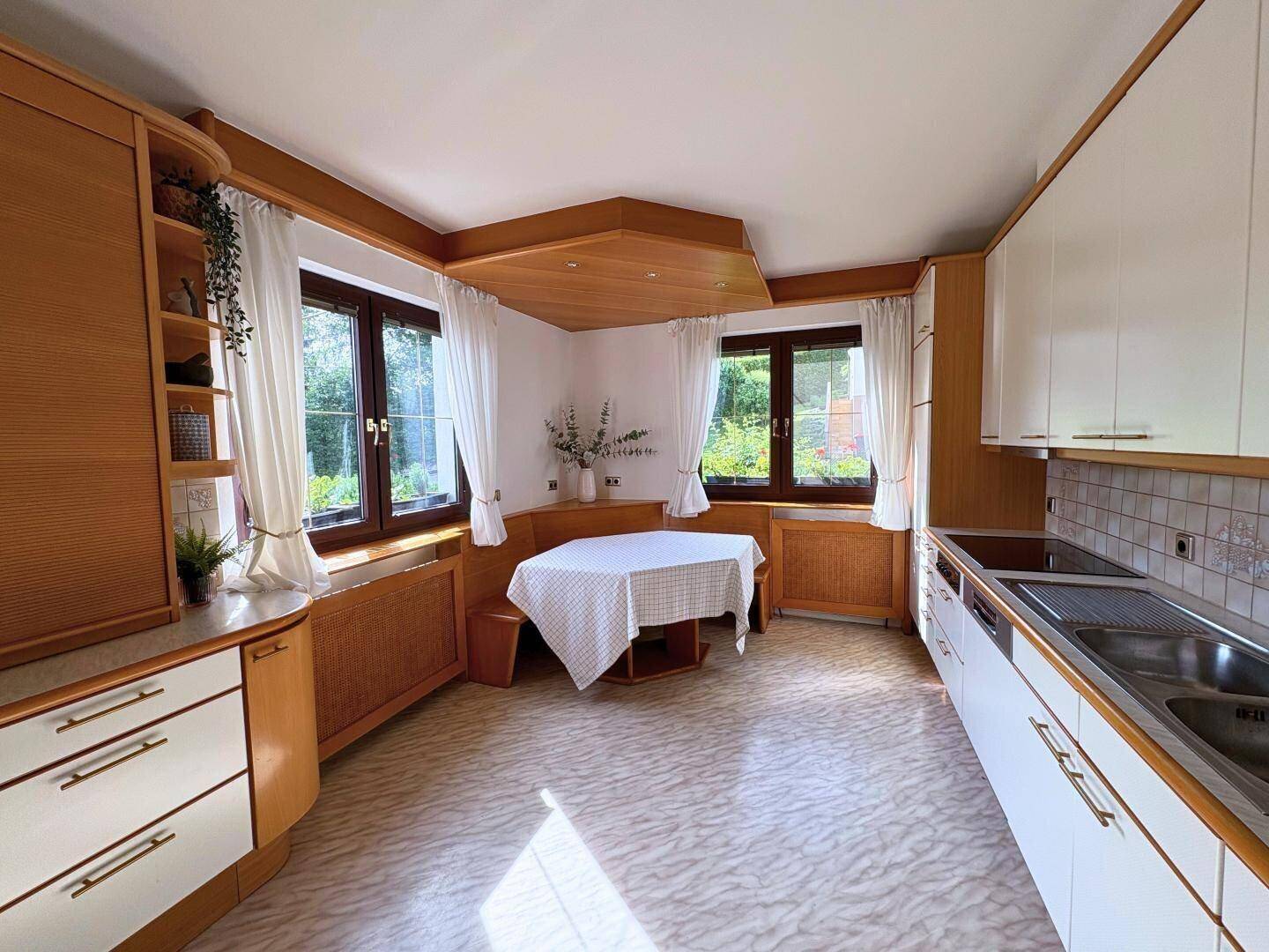 Gemütliche Wohnküche mit Holzelementen, Essbereich und Blick in den Garten.