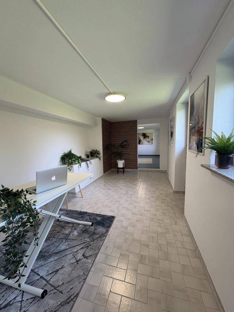 Langer Flur im Untergeschoss mit Fliesenboden und viel natürlichem Licht.