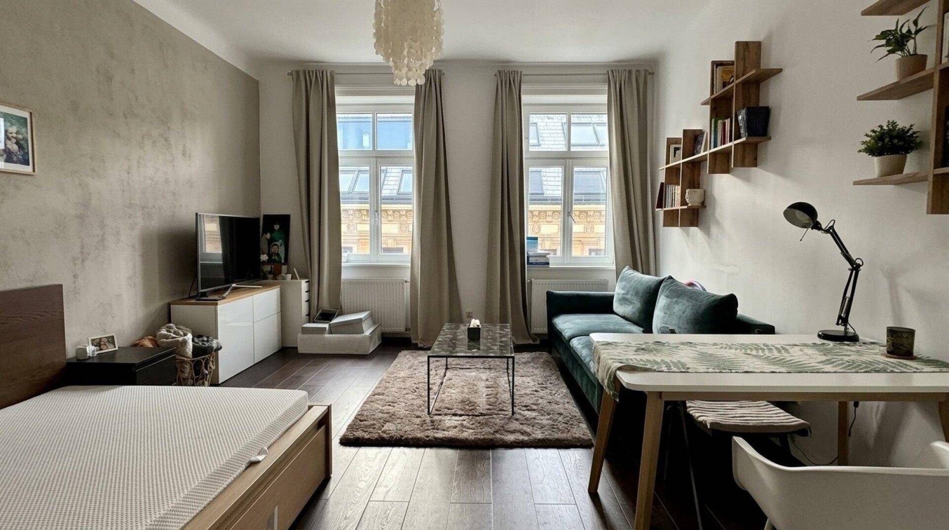 Heller Wohn- und Schlafbereich mit Holzboden, Sofa und Schreibtisch.