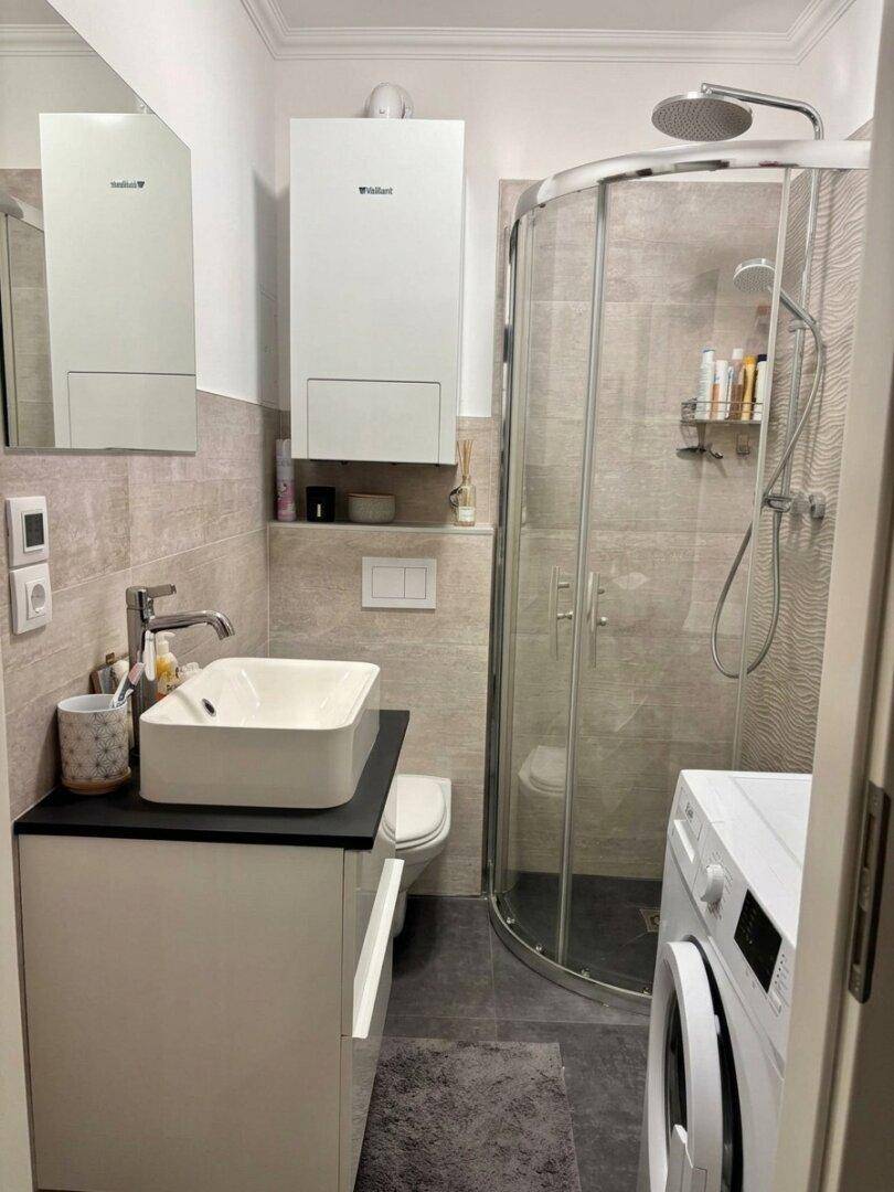 Modernes Badezimmer mit Duschkabine, Waschbecken und Waschmaschine.