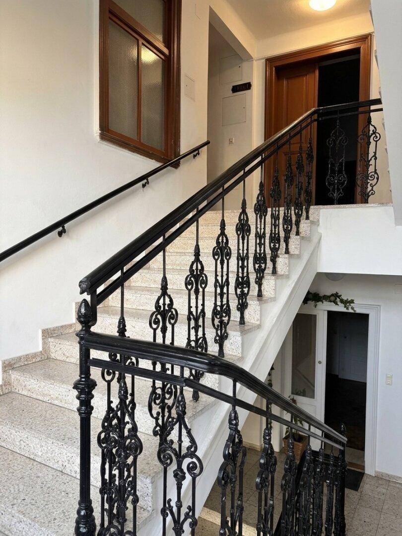 Elegantes Treppenhaus mit Marmorboden und kunstvollem Geländer.