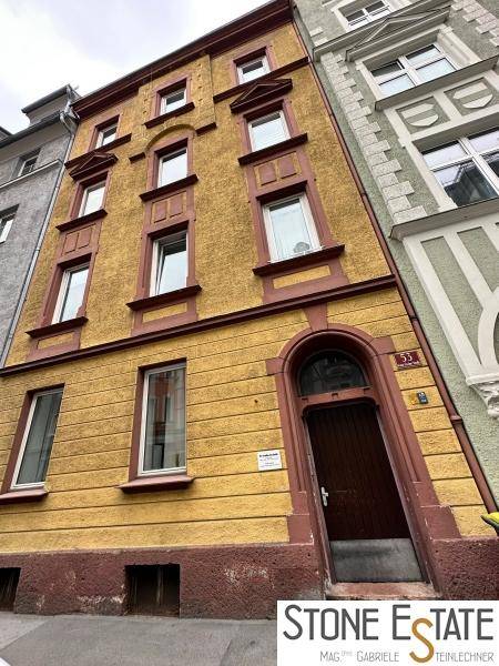 Detailansicht der gelben Fassade eines historischen Mehrfamilienhauses mit Holztür und Fenstern.