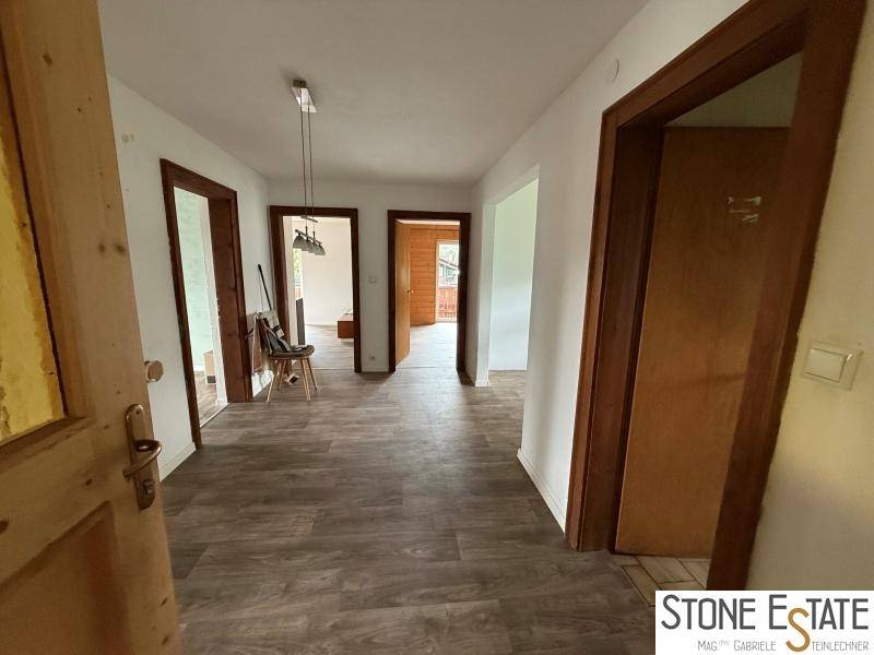 Geräumiger Flur mit Laminatboden und mehreren Holztüren zu den angrenzenden Zimmern.