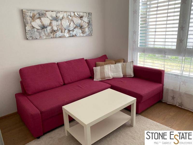 Gemütliches Wohnzimmer mit rotem Ecksofa, Couchtisch und Kunst an der Wand.