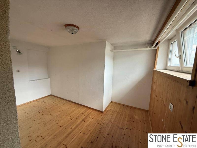 Gemütliches Zimmer mit Holzboden, Holzvertäfelung und Fenster für natürliches Licht.