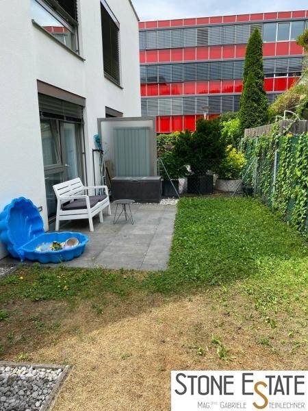 Hinterer Gartenbereich mit Terrasse, Rasen und Kinderspielzeug.