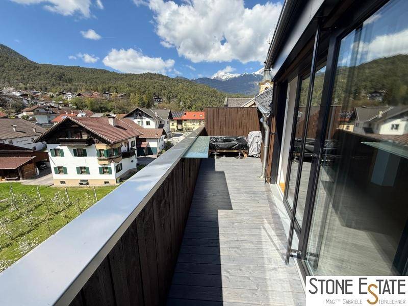 Langer Balkon mit Holzboden und weitem Blick auf die umliegende Berglandschaft.