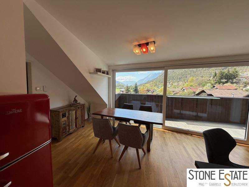 Essbereich mit Holztisch und Stühlen, großen Fenstern und weitem Blick auf die Berge.
