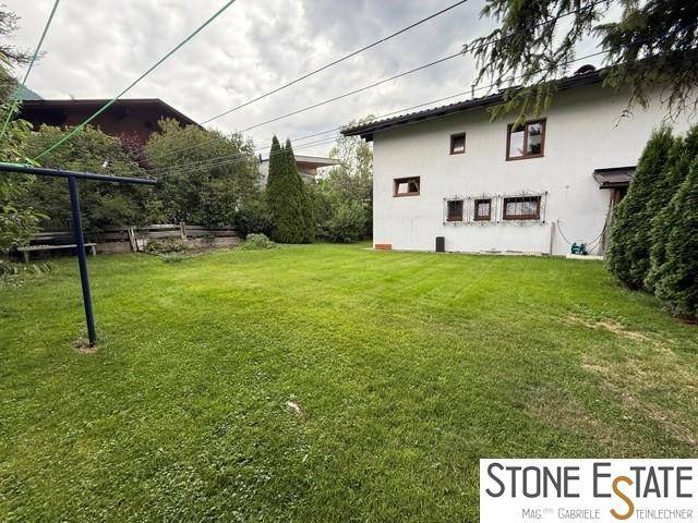 Großer, gepflegter Garten hinter dem Haus mit Wäscheleine und hohen Bäumen.