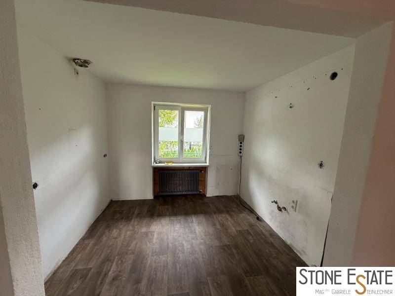 Leeres Zimmer mit Laminatboden, Fenster und Heizkörper, bereit zur individuellen Gestaltung.