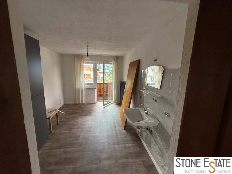 Heller Raum mit Waschbecken, Fliesenwand und Zugang zu einem Balkon.