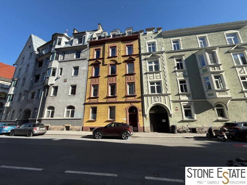 Historische Gebäudezeile mit unterschiedlichen Fassadenfarben an einer sonnigen Stadtstraße.