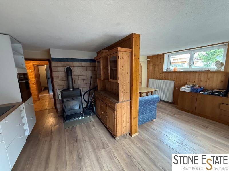 Wohn-Essbereich mit Holzofen, rustikalen Holzmöbeln und Holzvertäfelung.