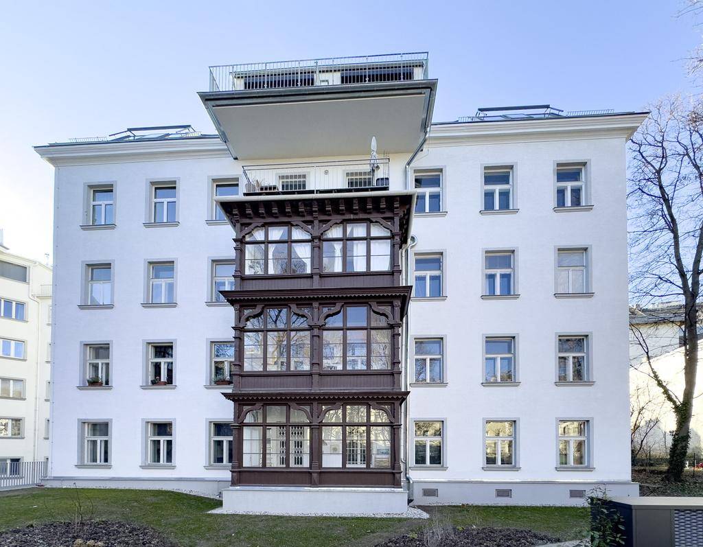 Ansicht des weißen Gebäudes mit markantem Erker und Dachterrasse an einem klaren Wintertag.