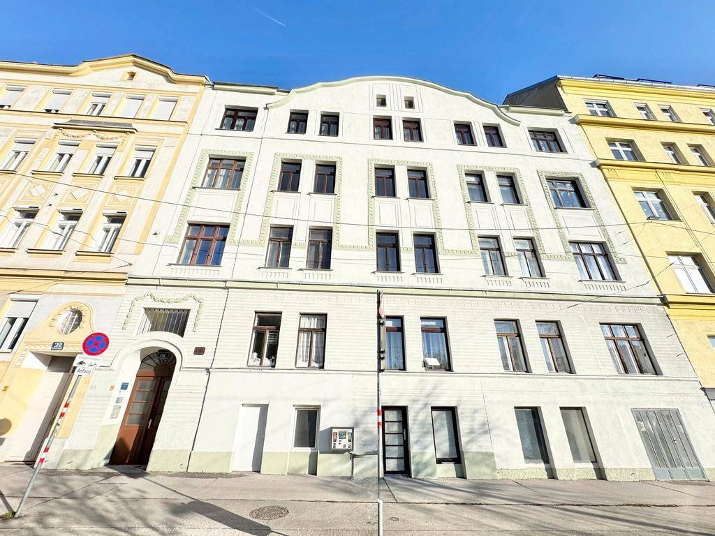 Historische Gebäudefassade mit mehreren Etagen und traditionellen Fenstern an einer Stadtstraße.