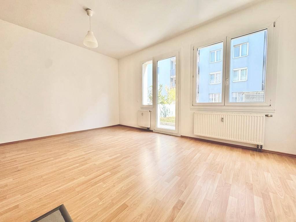 Lichtdurchfluteter Wohnraum mit Laminatboden und großen Fenstern, die viel Tageslicht hereinlassen.