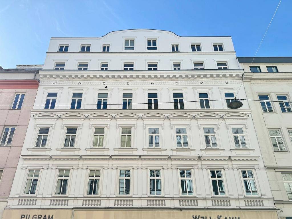 Historisches Gebäude mit frisch renovierter Fassade und modernen Dachgeschossfenstern.