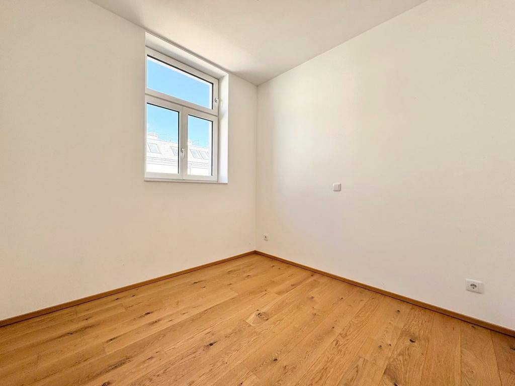 Freundliches Zimmer mit hellem Holzboden und Fenster, bietet viel Potenzial für verschiedene Nutzungen.