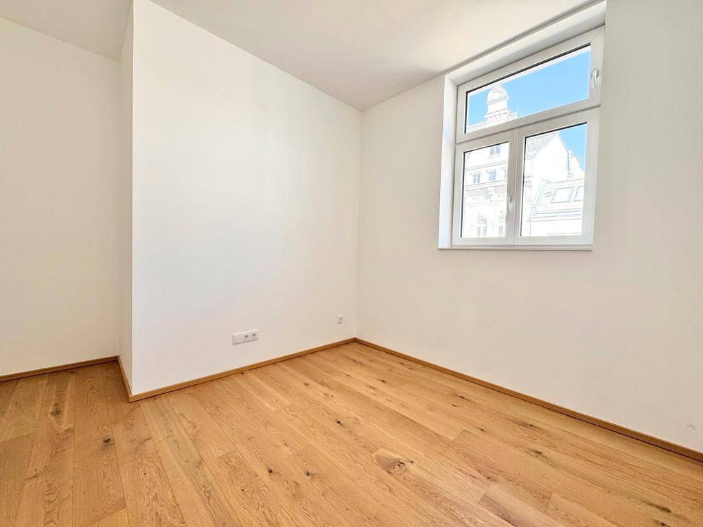 Lichtdurchfluteter Raum mit Parkettboden und einem großen Fenster, bereit zur individuellen Gestaltung.