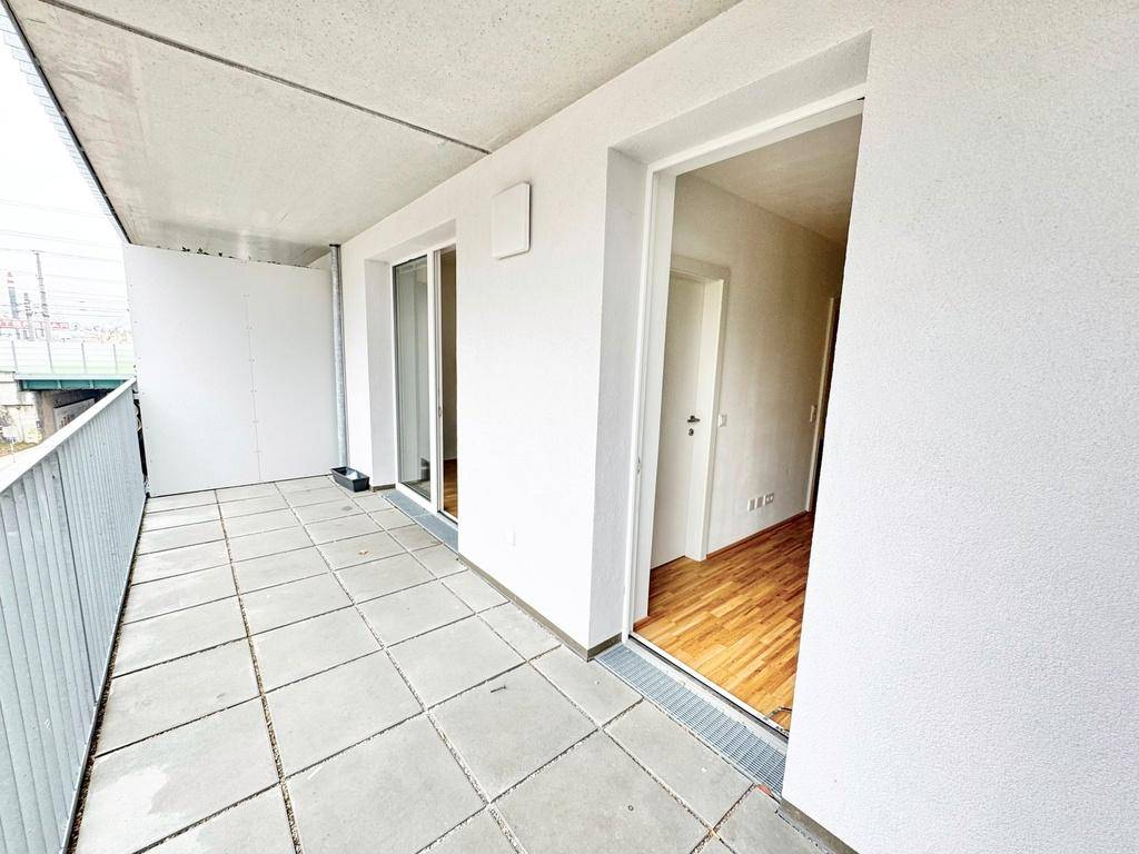 Heller Balkon mit Fliesenboden und direktem Zugang zu den Innenräumen der Wohnung.