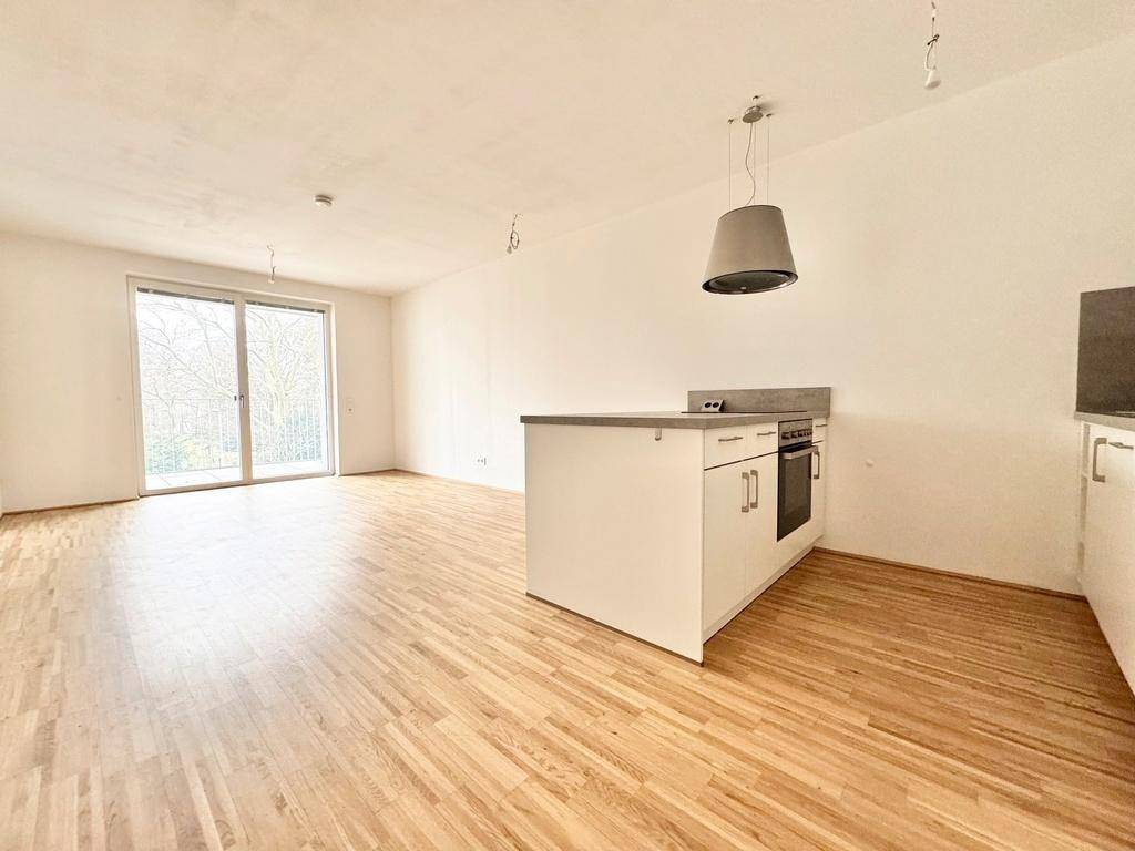 Offener Wohnbereich mit Parkettboden und einer modernen Kücheninsel, ideal für geselliges Beisammensein.