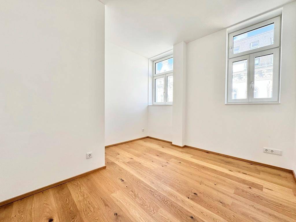 Helles Zimmer mit Eichenparkettboden und zwei großen Fenstern, ideal als Schlaf- oder Arbeitszimmer.
