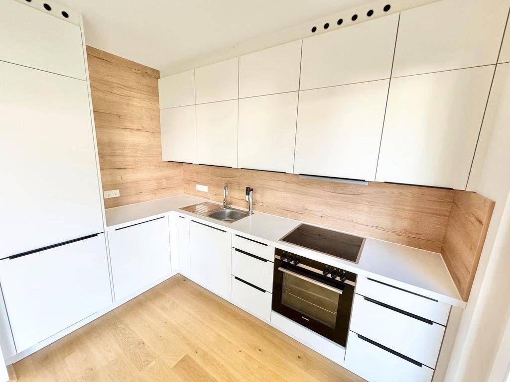Stilvolle Küche mit integrierten Geräten, weißen Schränken und Holzrückwand.