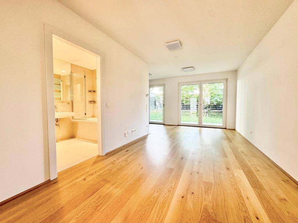 Heller Wohnbereich mit Holzboden und Zugang zu einem modernen Badezimmer.