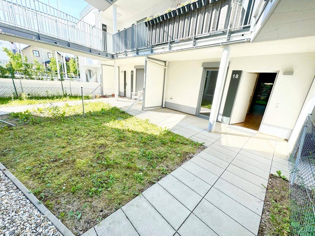 Außenansicht der Erdgeschosswohnungen mit privaten Gartenbereichen und Zugangswegen.