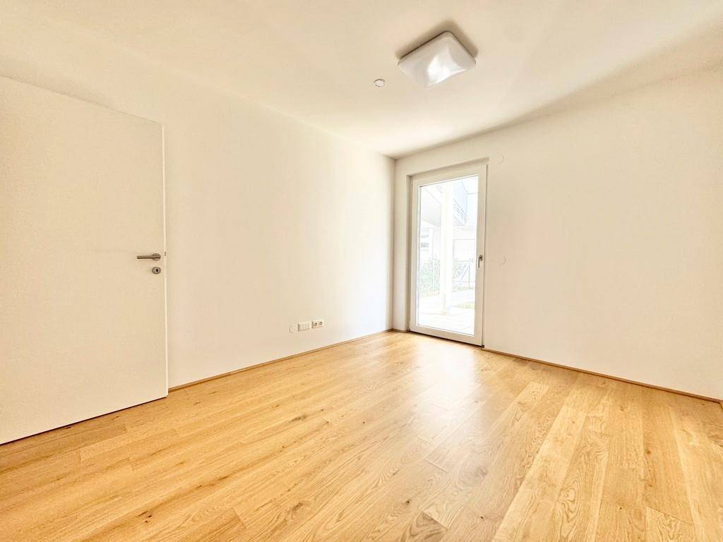 Helles Schlafzimmer mit Parkettboden und direktem Zugang zum Außenbereich.