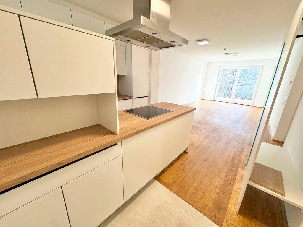 Helle, moderne Küche mit integrierten Geräten und Holzarbeitsplatten, offen zum Wohnbereich.