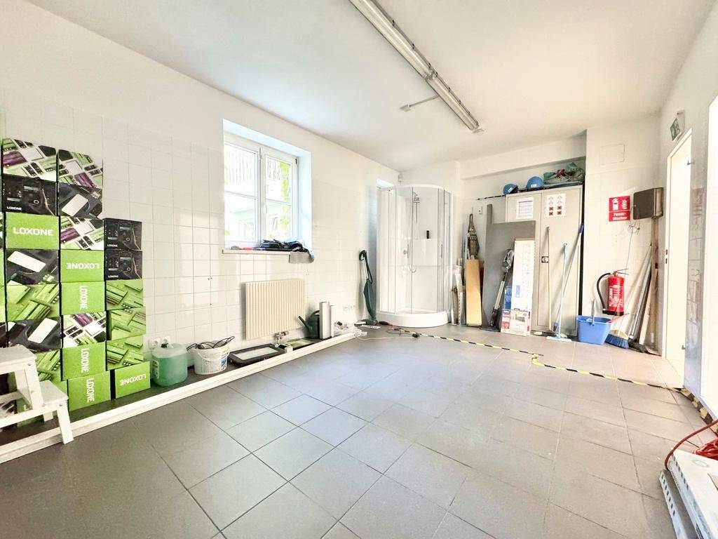 Hauswirtschaftsraum mit Duschkabine, Fenster und Lagerboxen, funktional und gut organisiert.