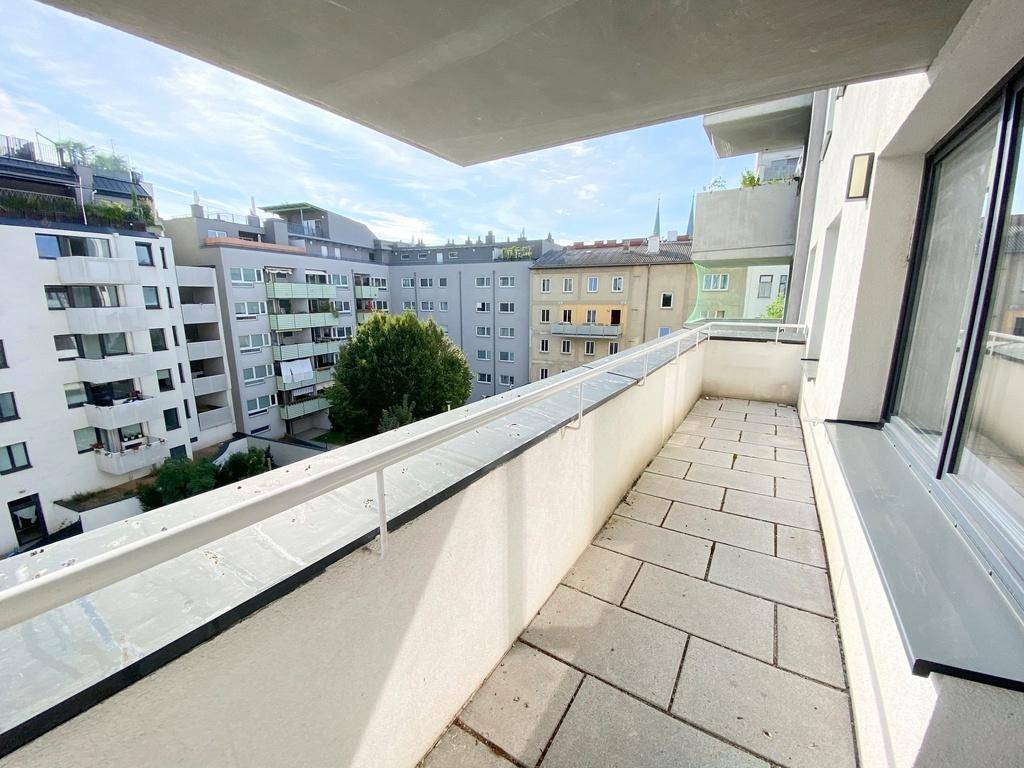 Heller Balkon mit Fliesenboden und Ausblick auf die Stadt und grüne Umgebung.